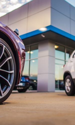 Automotive Dealership Store. New and Pre Owned Vehicles in Front of the Showroom Building.