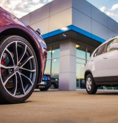 Automotive Dealership Store. New and Pre Owned Vehicles in Front of the Showroom Building.